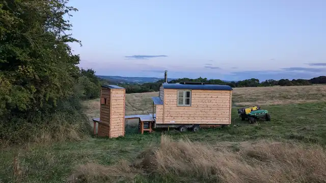 Interior of cosy off-grid cabin with king bed and log burner in Wales
